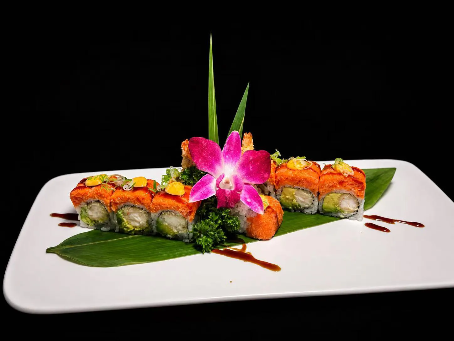 Salmon sushi roll topped with sauce and garnished with an orchid at Wasu Sushi Ramen, a Sushi restaurant in Bedminster